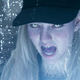 A young woman screams while she is surrounded by glowing blue sparks.